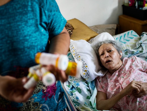 Marry Ann Aldea hands her mother medicine at her home in Juncos, Puerto Rico.DENNIS M. RIVERA PICHARDO/THE WASHINGTON POST/GETTY IMAGES